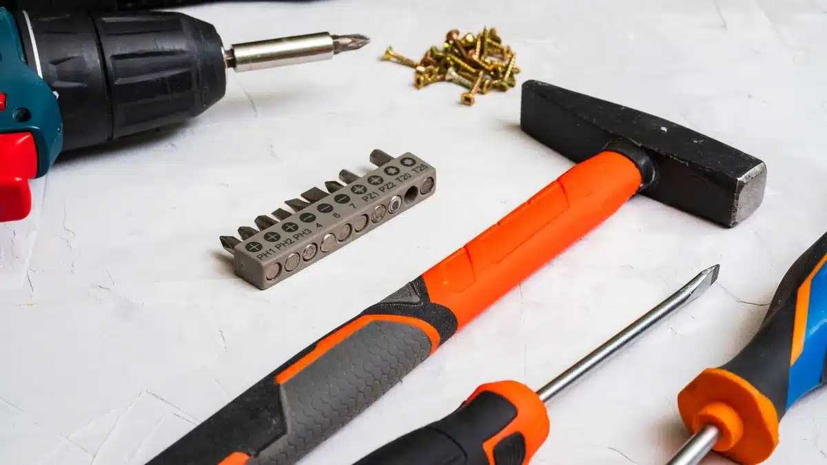 Outils d'installation pour motorisation de portail : perceuse, tournevis, niveau à bulle, pinces