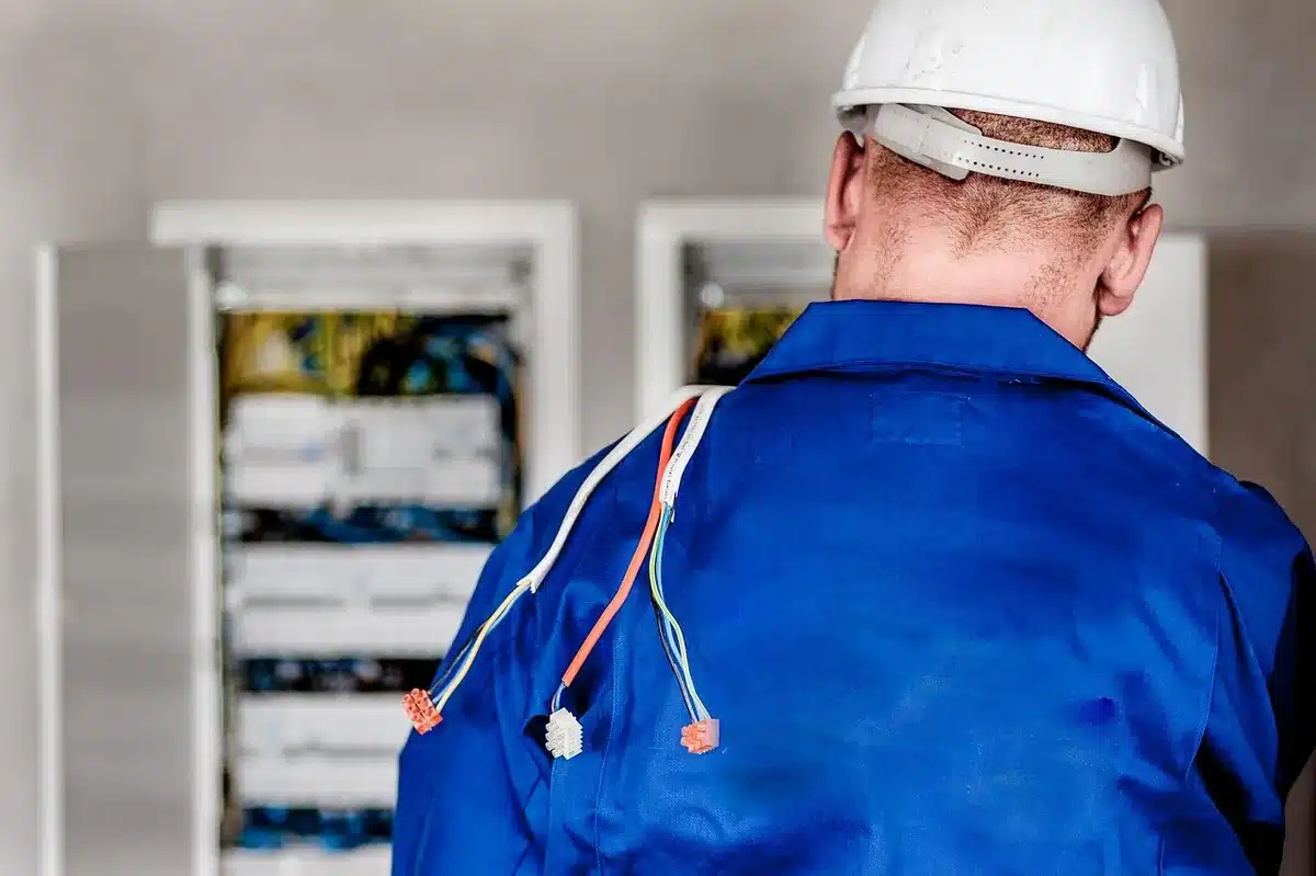 Électricien réalisant le câblage des panneaux au plafond dans une pièce claire